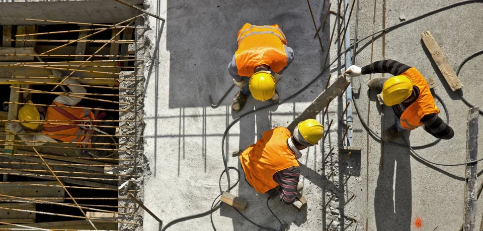 Construction workers beside a reinforced concrete building